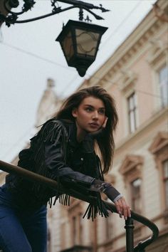 a woman leaning up against a lamp post