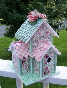 a birdhouse made out of crochet is sitting on a white bench in the grass