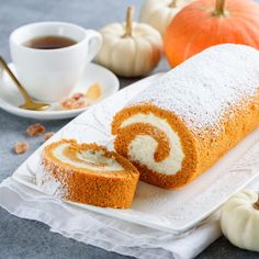 there is a roll that has been cut in half on a plate next to some pumpkins