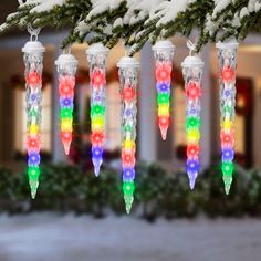 multicolored wind chimes hanging from a christmas tree in front of a house