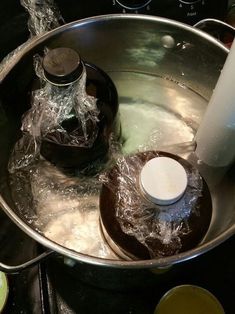 a large metal bowl filled with water next to a white bottle on top of a stove