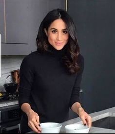 a woman standing in front of a counter holding a plate with food on top of it