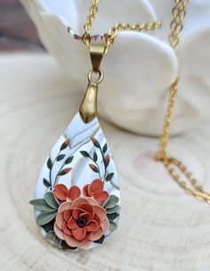 a necklace with an orange flower hanging from it's side on a gold chain