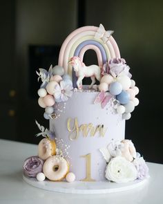 a birthday cake decorated with pastel flowers and unicorns is on a white table