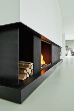 a fire place with logs in the center and white walls behind it, on top of a green floor