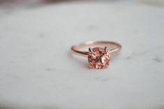 a pink diamond ring sitting on top of a table