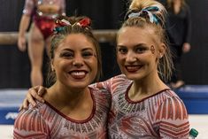 two young women standing next to each other in front of a stage with one holding her arm around the other's shoulder