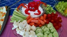 there is a platter with vegetables and crab on the plate next to other foods