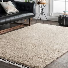 a living room with a black couch and white rug