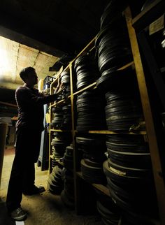 a man standing next to a shelf filled with tires