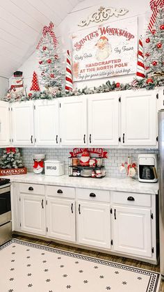 a kitchen decorated for christmas with white cabinets and silver stove top oven, holiday decorations on the wall