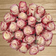 a bouquet of pink roses sitting on top of a wooden table