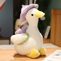 a white duck with a purple hat sitting on top of a wooden table next to a newspaper