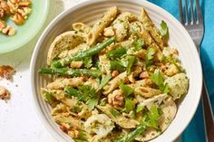 a bowl filled with pasta and vegetables on top of a blue napkin next to a fork