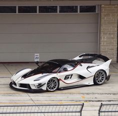 a white and black sports car parked in front of a garage door on the street