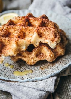 a waffle on a plate with lemon wedges