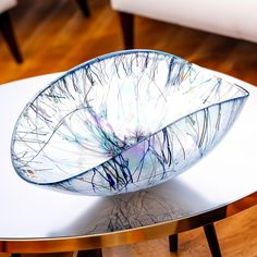 a glass bowl sitting on top of a white table next to a wooden coffee table