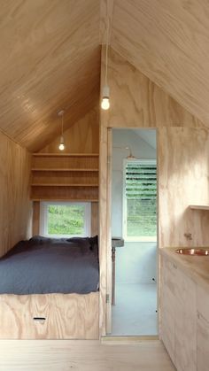 a bed in a small room with wooden walls and flooring that is made out of plywood