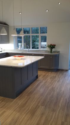 a large kitchen with wooden floors and gray cabinets