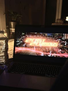 an open laptop computer sitting on top of a table next to a bottle of water