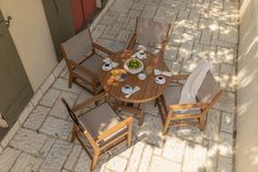 a wooden table with chairs and plates of food sitting on it's outside patio