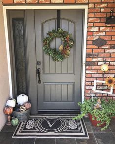 a front door with a wreath and pumpkins on the side walk next to it