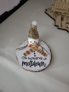 a snowman ornament is sitting on top of a white surface with the words i'm having a meltatinn