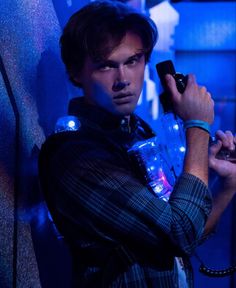 a man holding a cell phone up to his ear in front of a blue background