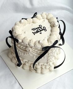 a white cake with black ribbon and happy birthday written on it