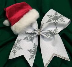 a white bow with silver snowflakes on it and a santa hat on top