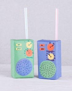 two colorful boxes with straws in them sitting side by side on a white surface