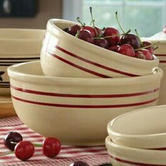 several bowls with cherries in them on a table cloth next to plates and utensils