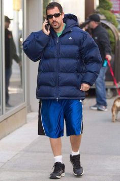 a man is walking down the street talking on his cell phone while holding a dog