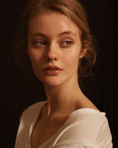 a woman in white is posing for a photo with her eyes wide open and looking at the camera