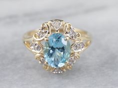 an oval blue topazte and diamond ring on a white surface with gold accents