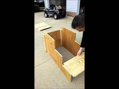 a man standing over a wooden box on top of a cement floor next to a truck