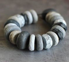 a close up of a bracelet made out of rocks on a table with a black and white bead around it