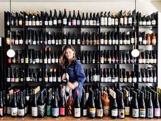 a woman standing in front of a wall full of wine bottles