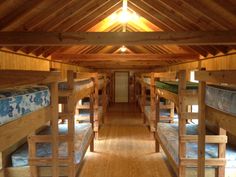 there are many bunk beds in this small room with wood flooring and wooden walls