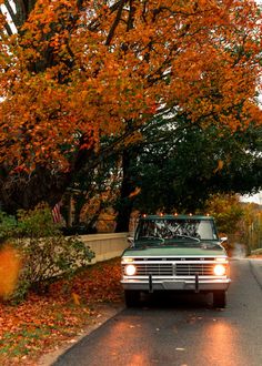 an old truck is parked on the side of the road in front of some trees