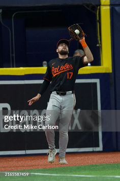 a baseball player catching a ball in the air with his glove out and one hand up