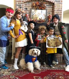 a family dressed up in costumes posing for a photo with their dog and two children