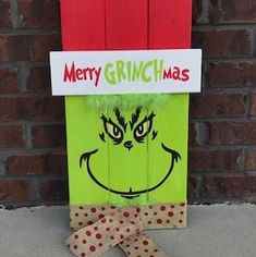 a green bag with a grin face on it and a red ribbon tied to the front