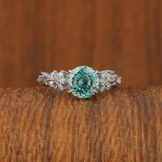 a blue diamond ring sitting on top of a wooden table