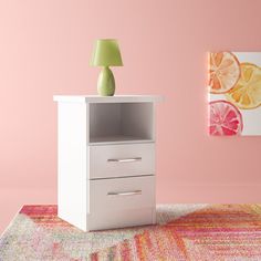 a white cabinet sitting on top of a rug next to a wall with a lamp