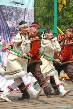 several people dressed in traditional russian costumes are performing on stage with poles and poles attached to their backs