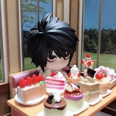 a table topped with cakes and cupcakes next to a window filled with lots of windows