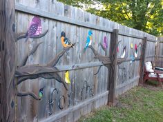 a wooden fence with birds painted on it and hooks attached to the fence posts, along with a bench