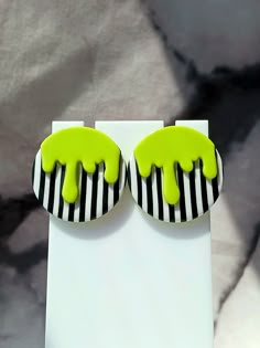 two black and white striped earrings with neon green paint dripping down the side of them