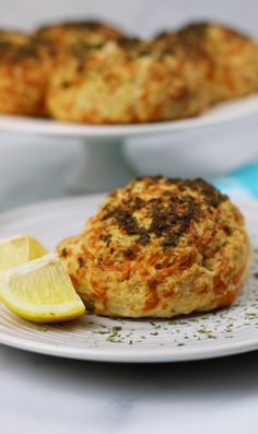 some food is on a white plate with a lemon wedge next to it and another dish in the background